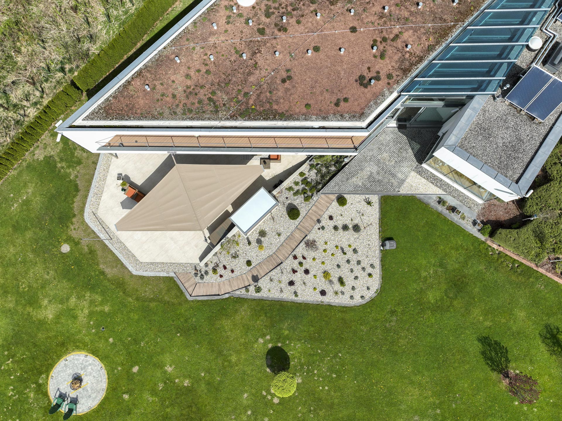 Das ausgefahrene beige Doppel Dreieck Sonnensegel seitlich zum Rauten förmigen Haus