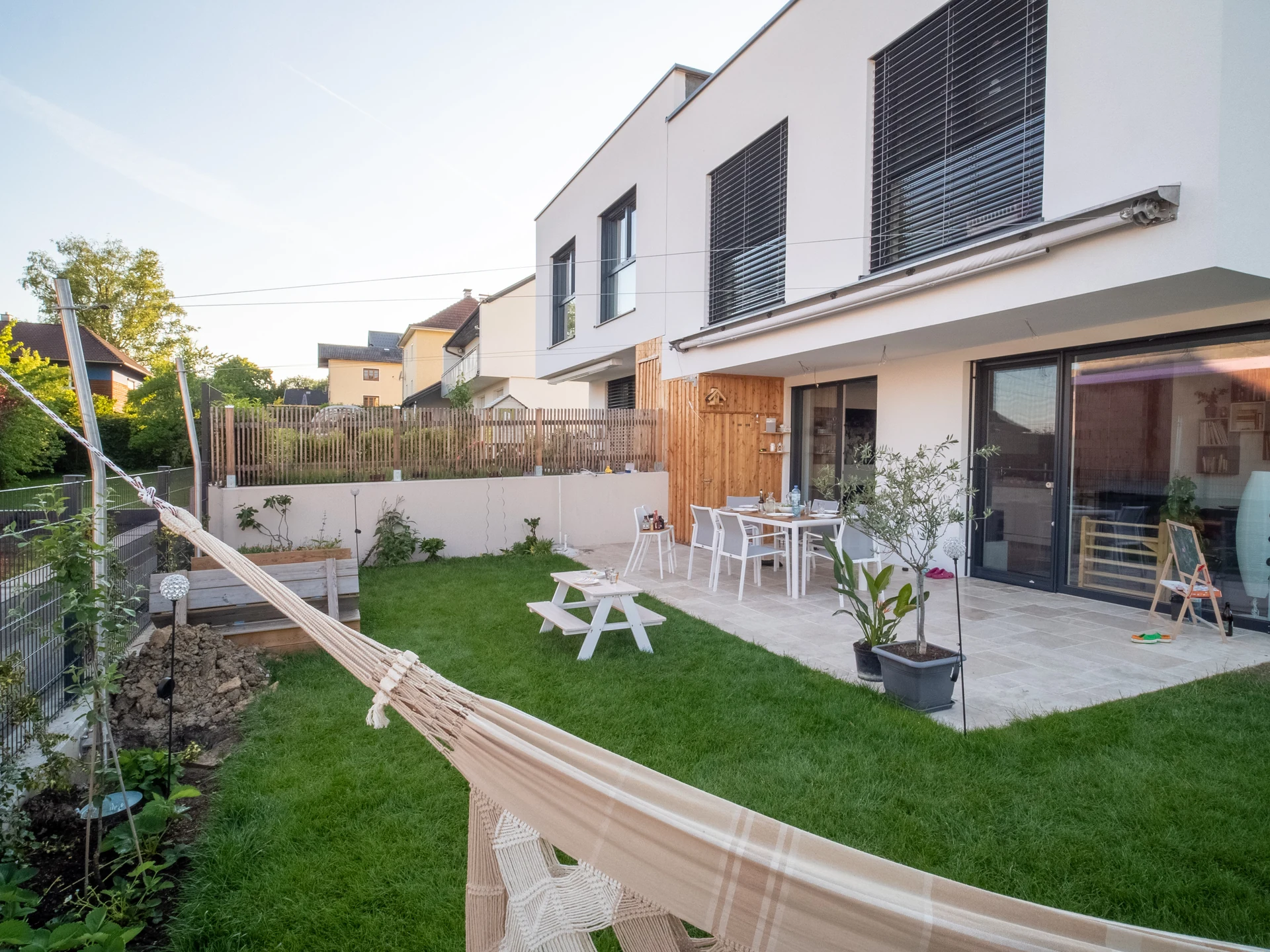 Terrasse eines Doppelhauses mit Sonnensegel am Abend