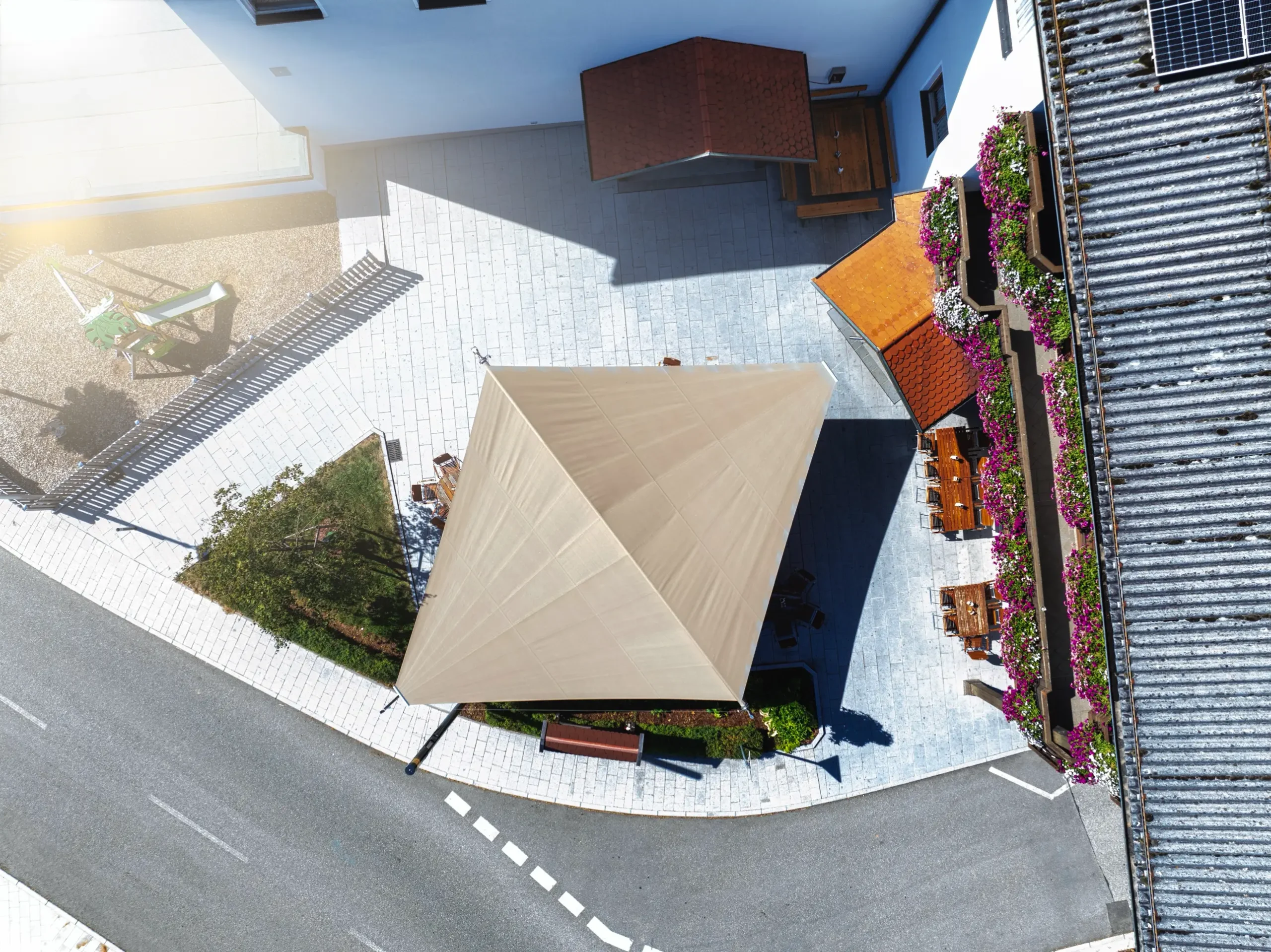 Draufsicht auf das großflächige Sonnensegel am Gemeindeplatz St. Aegidi, das sich harmonisch zwischen Kirchenwirt und Ortskern einfügt.