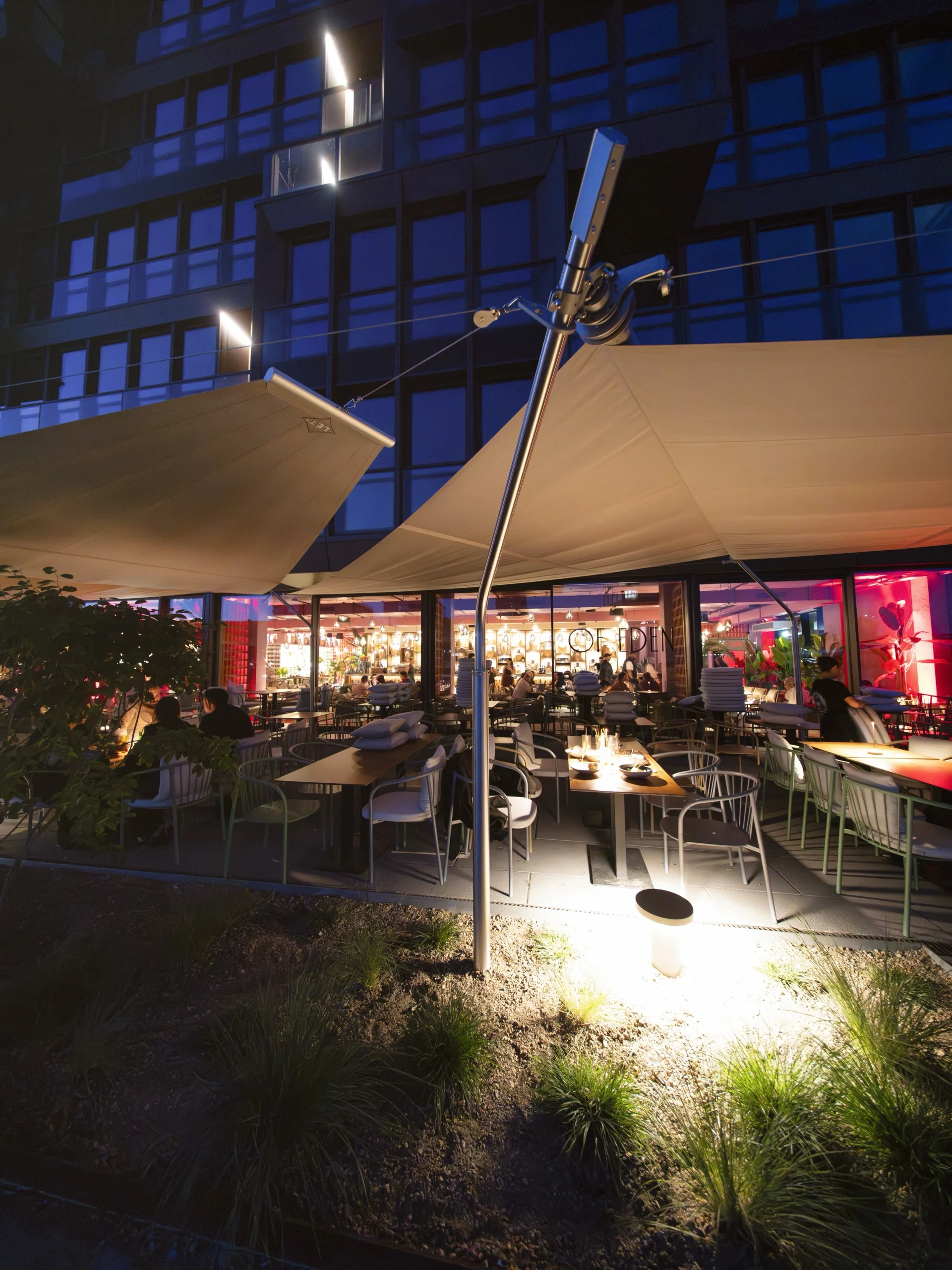 Of Eden Berlin bei Nacht mit beleuchtetem Sonnensegel über der Terrasse