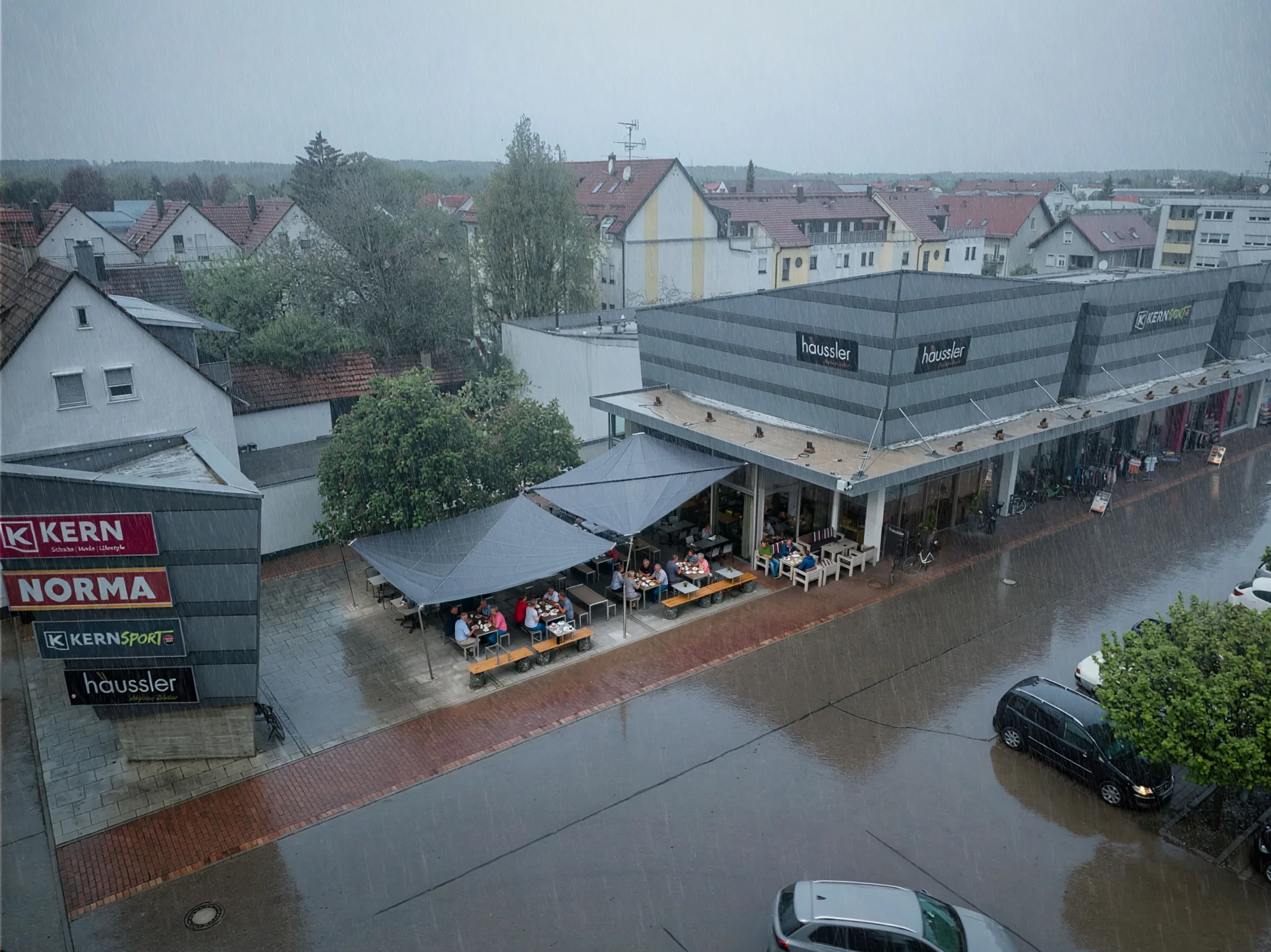 Gäste sitzen bei Regen geschützt unter dem Sonnensegel der Terrasse von Backhaus Häussler in Illertissen