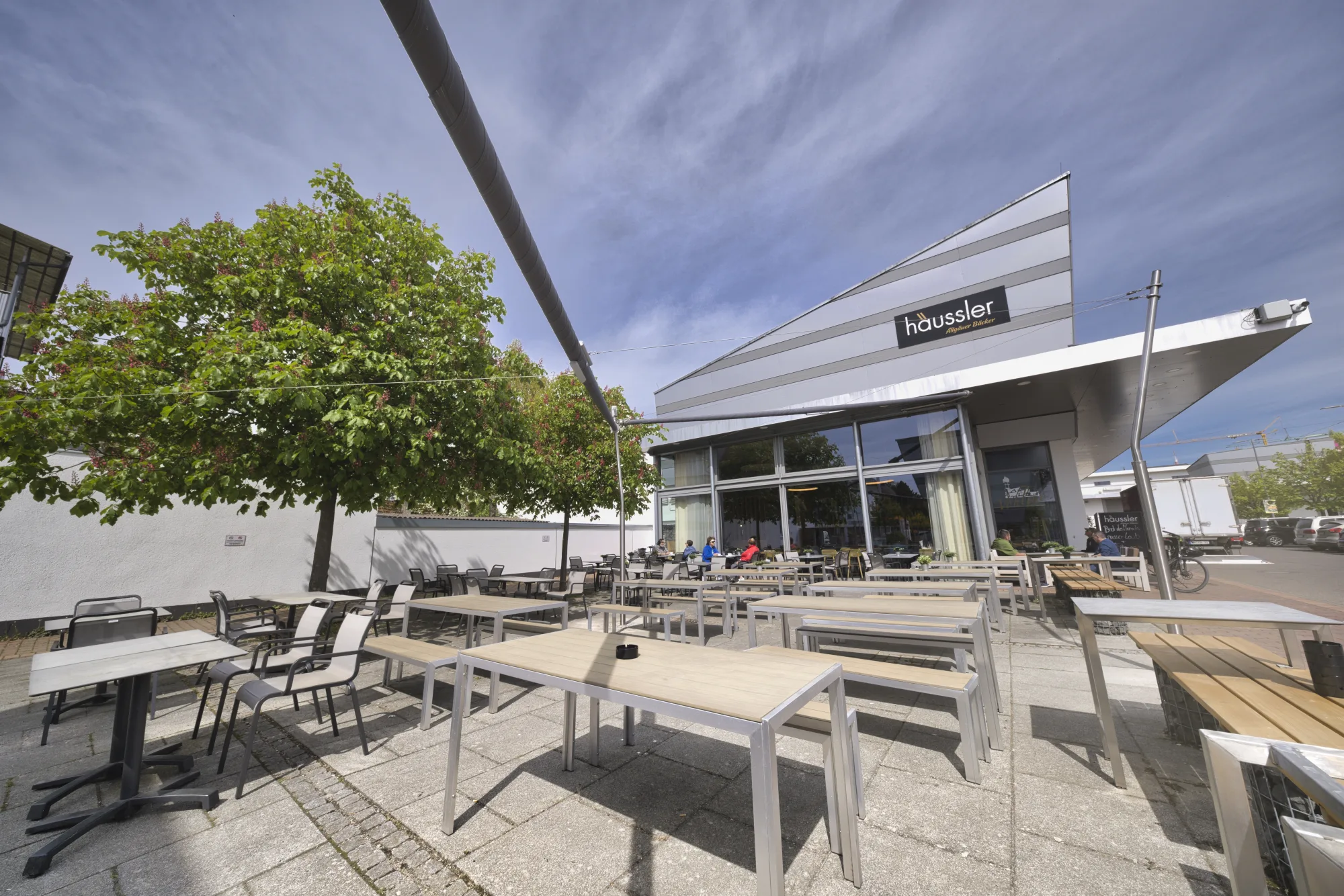 Weite Café-Terrasse von Backhaus Häussler unter den Sonnensegeln