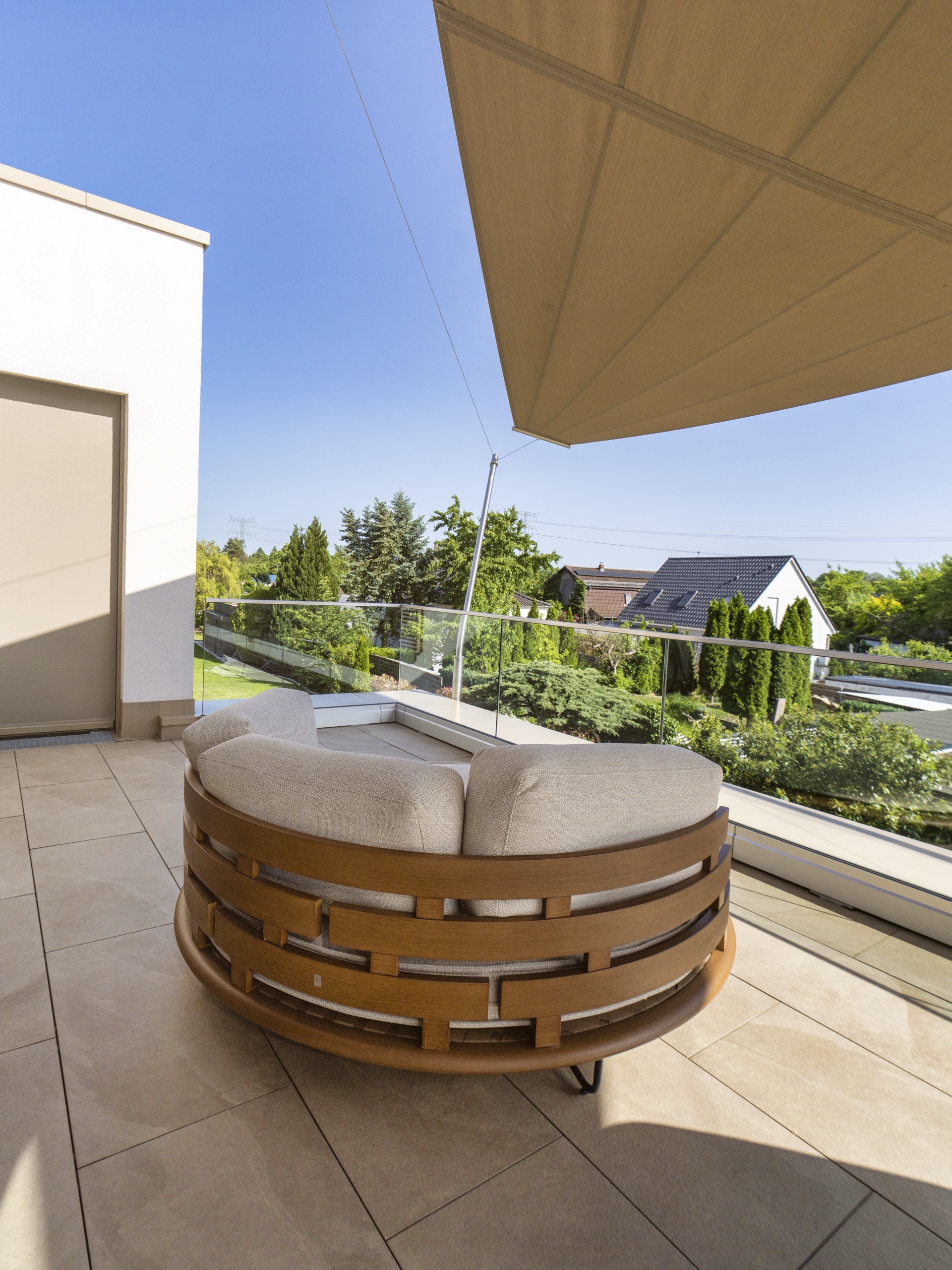 Rundes Lounge-Daybed im Schatten des Sonnensegels auf der Berliner Dachterrasse