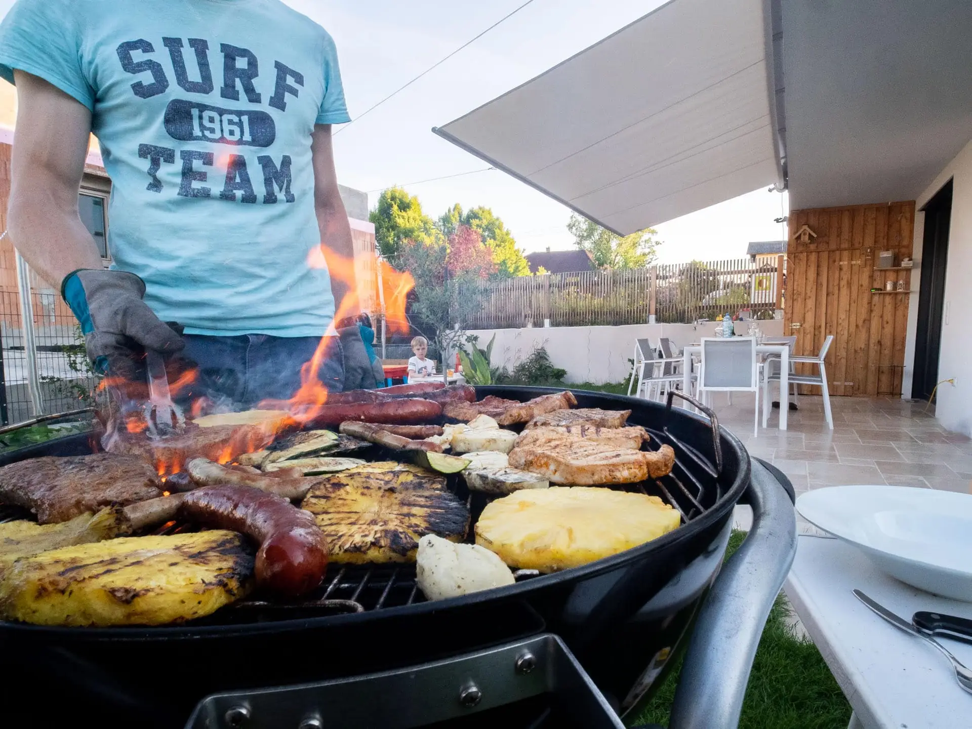 Familie grillt unter Sonnensegel Terrassenüberdachung nach Maß – Doppelhaus Linz von LET