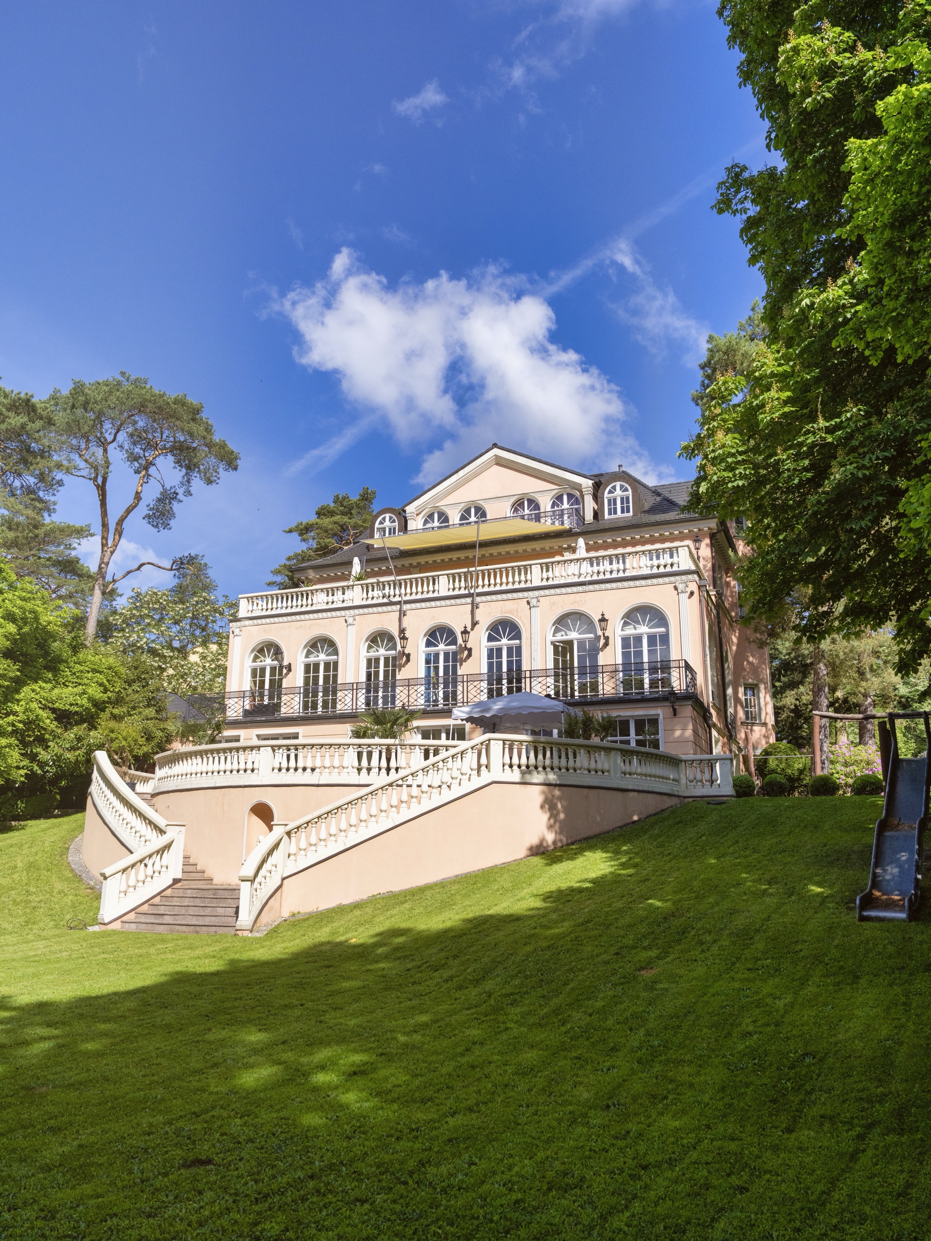 Herrschaftliche Villa vom Garten aus mit geschwungener Freitreppe