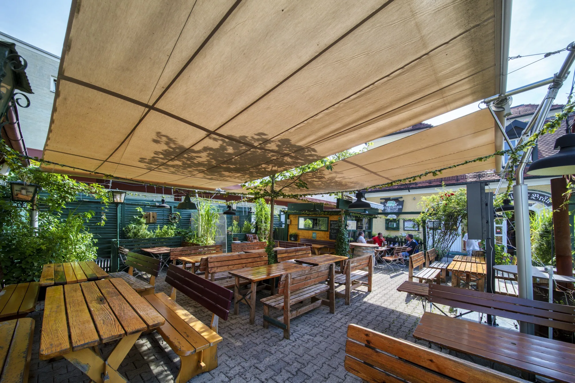 Biergarten des Wieninger Bräu unter den beiden Trapez-Sonnensegeln, Blick über die Tische